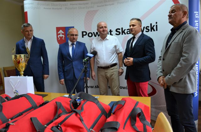 Uczestnicy spotkania stoją na tle ścianki wizerunkowej powiatu 