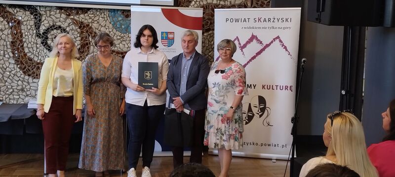 laureat konkursu odbierajacy dyplom i nagrodę wraz z przedstawicielami szkoły 