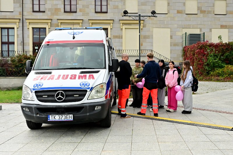 grupka młodzieży z sanitariuszami przy karetce pogotowia