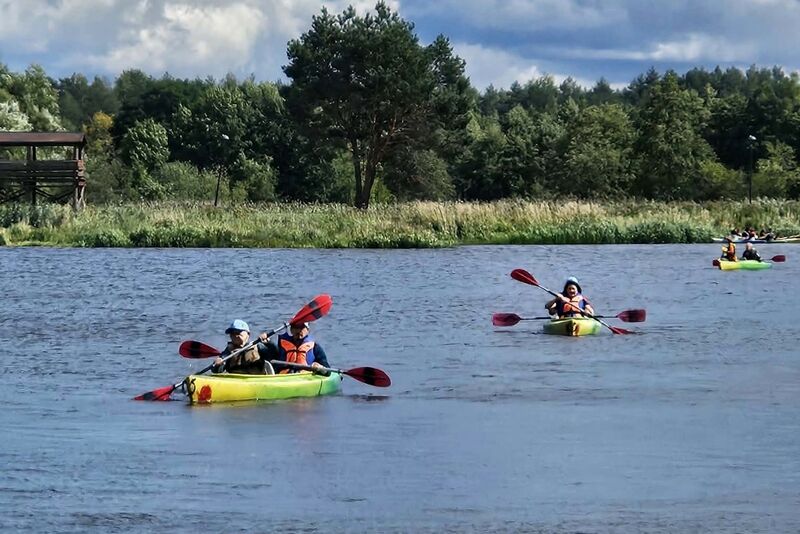 kilka kajaków płynących po jeziorze na tle lasu