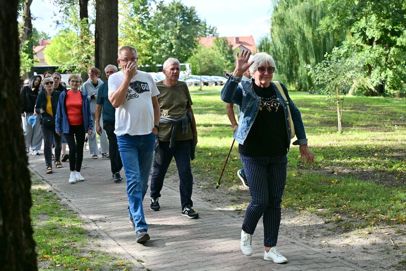 kobieta machająca do obiektywu podczas spaceru z grupą turystów w parku w Zwierzyńcu
