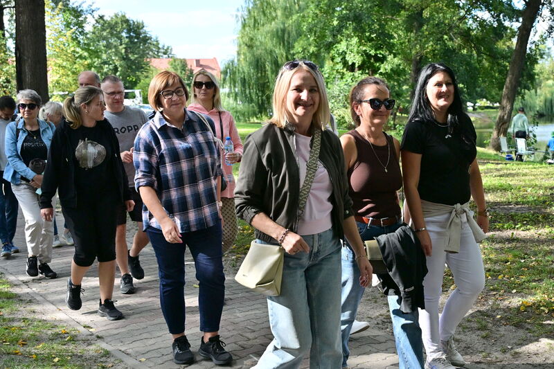 grupa uśmiechniętych kobiet idących aleją w parku