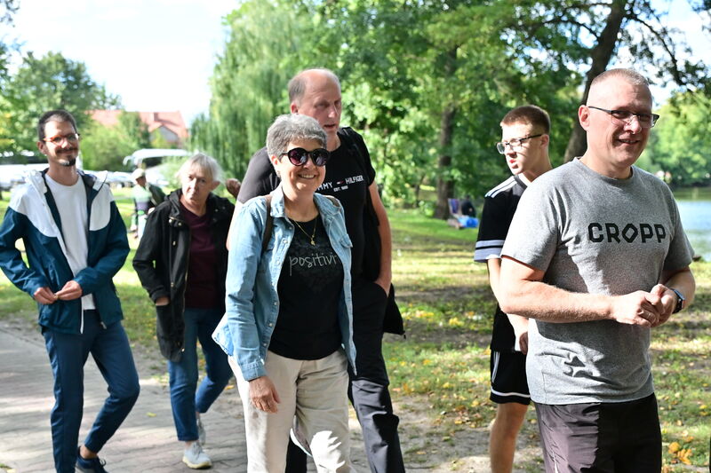 zadowolona grupa osób idąca aleją w parku