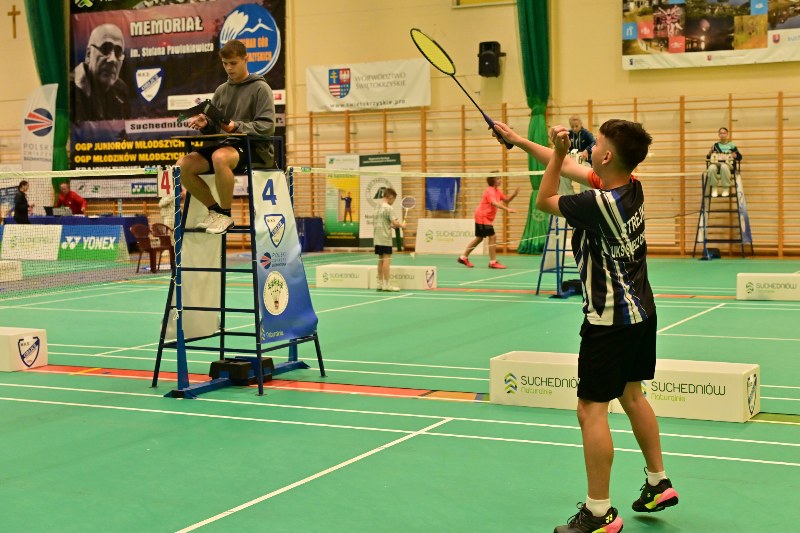 zawodnik z rakietą na hali sportowej i na podwyższonym krzesełku sędzia