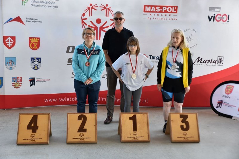 3 zawodniczki z trenerem na podium