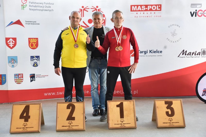 2 mężczyzn na podium z trenerem